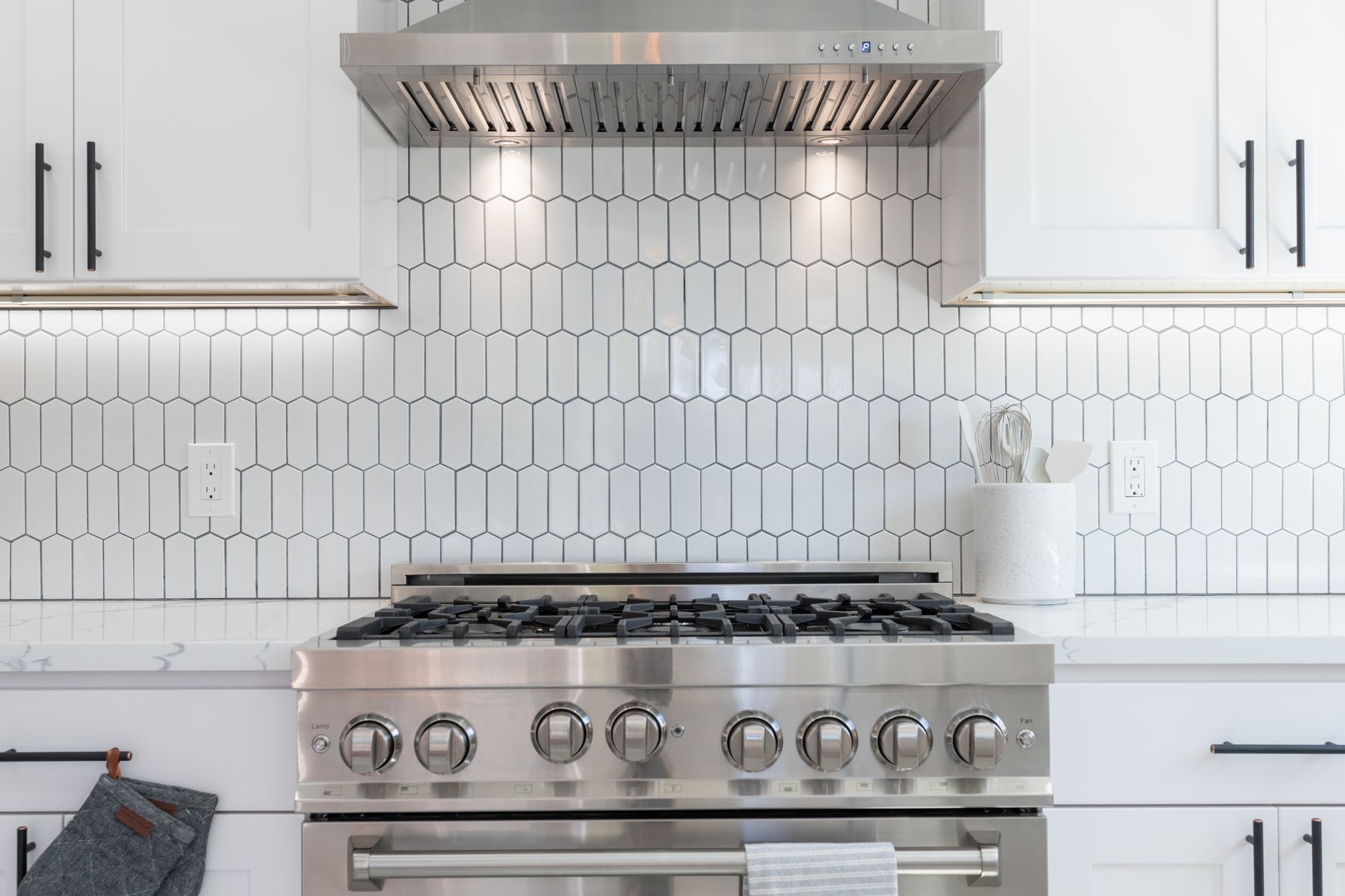 White hexagon tile backsplash behind a range