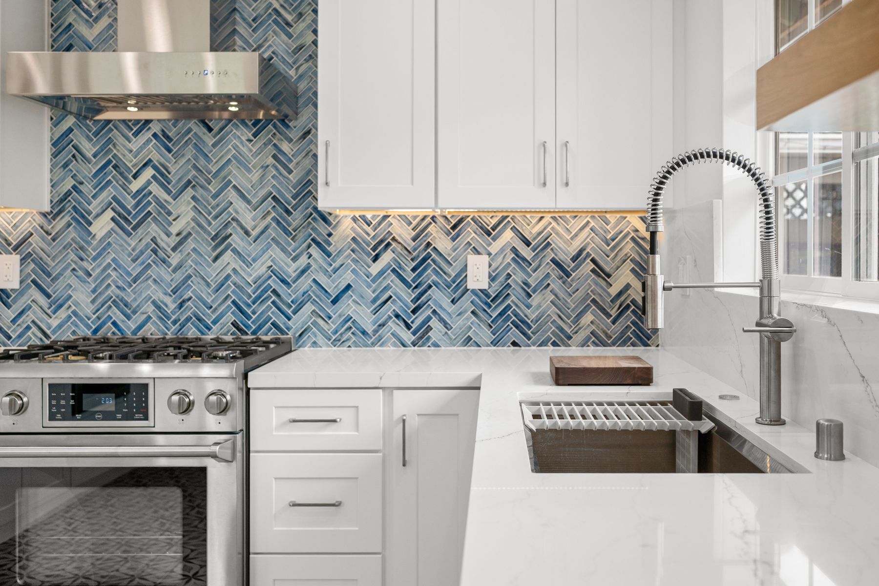 White quartz counters with a blue herringbone backsplash