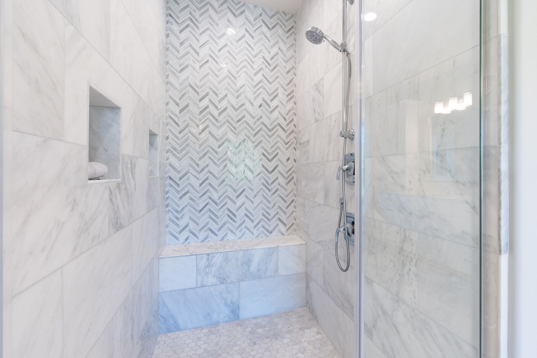 White marble herringbone walk-in shower with bench in Fort Walton Beach, FL